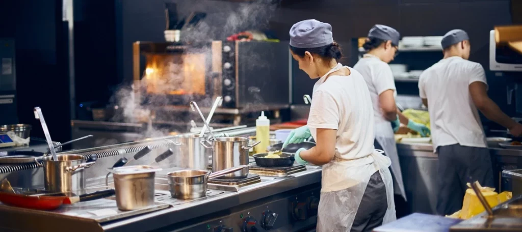 Küchenpersonal bereitet verzehrfertige Speisen in einer professionellen Gastronomieküche zu – Symboldbild für Ermäßigter Steuersatz für Verpflegungsleistungen