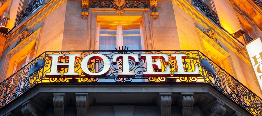 Beleuchtetes Hotelschild an einer klassischen Fassade bei Nacht – Symbolbild für Beherbergungsleistungen und Hotel-Nebenleistungen.